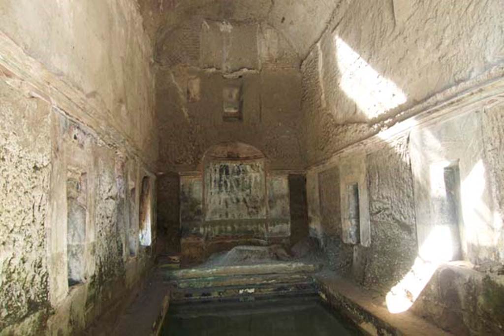 South-western baths, Herculaneum. July 2010. Room 1, interior of baths complex.
Photo courtesy of Michael Binns.
At the north end of the hot pool was a nymphaeum.
On either side of the nymphaeum would have been a narrow doorway into room 3 and other rooms of the baths complex.
Also, on the short, north side of the pool were steps descending into the water.
On the two long sides of the pool were a total of six rectangular windows, three on each side.
These have not yet been cleared of their pyroclastic material.
There are rectangular niches visible between the windows.